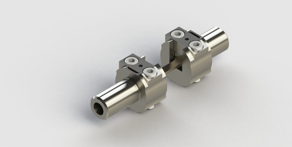 Eine Nahaufnahme von zwei miteinander verbundenen mechanischen Metalleinspannungen. Jede Kupplung besteht aus zylindrischen Teilen mit Bolzen an der Oberseite und einem hohlen Zentrum. Der Hintergrund ist schlicht weiß.