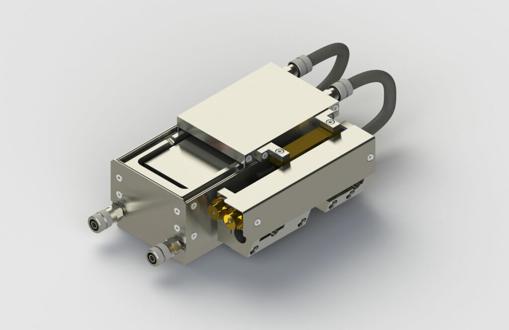 Ein metallisches mechanisches Gerät, bekannt als Transfer-Modul, an das zwei sichtbare Schläuche angeschlossen sind. Das Gerät besteht aus verschiedenen miteinander verbundenen Komponenten, darunter Schrauben, einem flachen rechteckigen Oberteil und zylindrischen Elementen. Der Hintergrund ist schlicht und hellgrau.